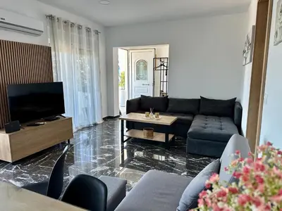 a living room with a couch and a tv at Aikaterini Lever Du Soleil Apart, Koskinou in Koskinou