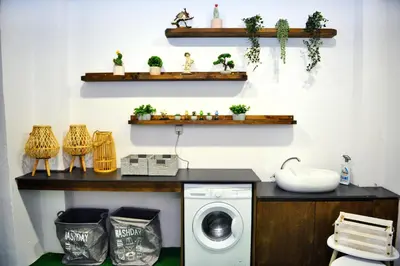 a laundry room with a washing machine and shelves with plants at Aikaterini Lever Du Soleil Apart, Koskinou in Koskinou