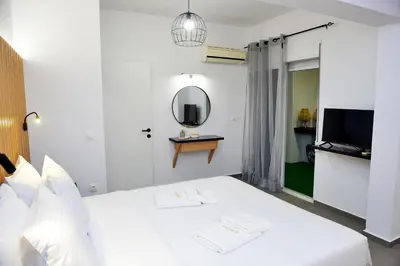 a bedroom with a white bed with a mirror and a tv at Aikaterini Lever Du Soleil Apart, Koskinou in Koskinou