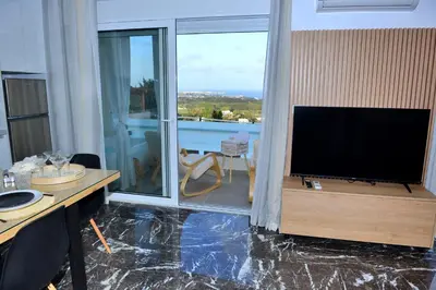 a living room with a flat screen tv and a desk at Aikaterini Lever Du Soleil Apart, Koskinou in Koskinou