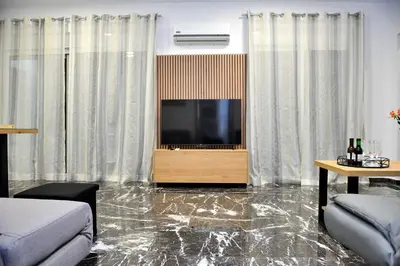 a living room with a tv and a marble floor at Aikaterini Lever Du Soleil Apart, Koskinou in Koskinou