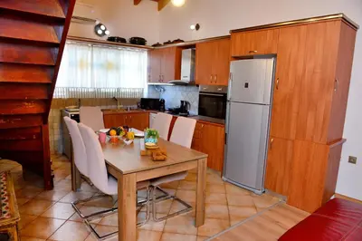 a kitchen with a wooden table and a white refrigerator at Unique Smaragda's Residense in Rhodes Town