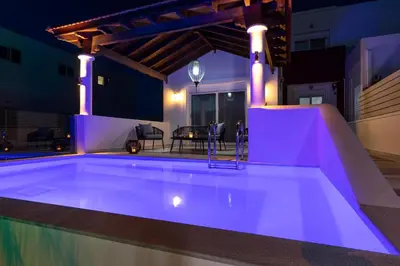a swimming pool lit up at night with purple lights at Elena House in Gennadi