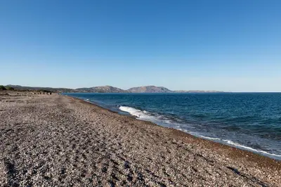a rocky beach with water and mountains in the background at Elena House in Gennadi