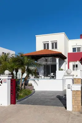 a white house with a red door and palm trees at Elena House in Gennadi