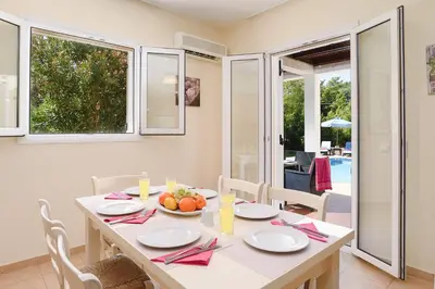 a white dining room with a table and chairs at Seven Springs Villas in Kolimbia