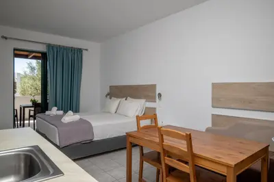 a bedroom with a bed and a table and a sink at Triantafillas Suites in Afantou