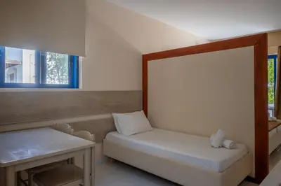 a room with a bed and a table and a window at Triantafillas Suites in Afantou
