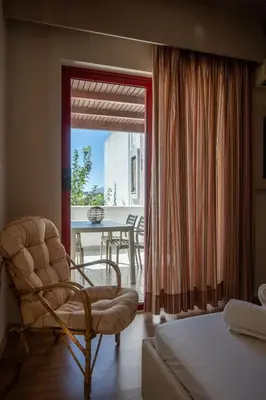 a bedroom with a chair and a table with a view at Triantafillas Suites in Afantou