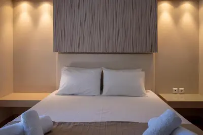 a bed with two white pillows and two towels at Triantafillas Suites in Afantou