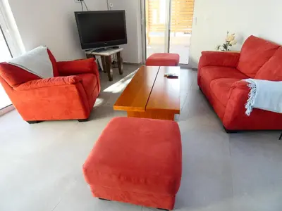a living room with red furniture and a tv at Louloudi Hills Villa 3 in Koskinou