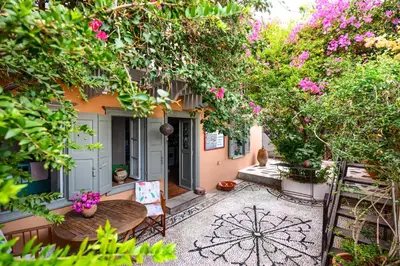 a garden with a table and chairs and flowers at Villa Melograno HALKI in Halki