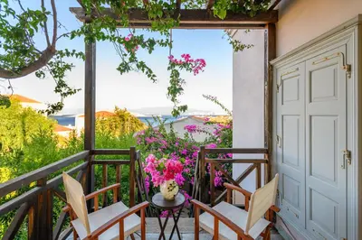 a balcony with chairs and a table and flowers at Villa Melograno HALKI in Halki