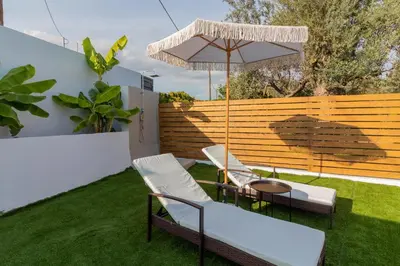 a patio with two chairs and a table and an umbrella at Melia Luxury Villa in Kolimbia