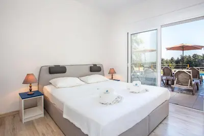 a bedroom with a large bed and a balcony at Louloudi Hills Villa 1 in Koskinou
