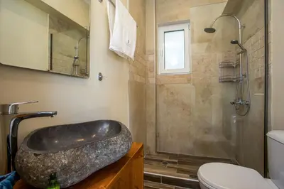 a bathroom with a stone sink and a shower at Louloudi Hills Villa 1 in Koskinou