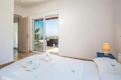 a bedroom with a large white bed with a view at Louloudi Hills Villa 1 in Koskinou