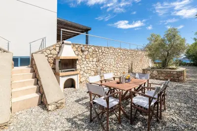 a patio with a table and chairs and a stone wall at Villa Mare di Levante with Private Pool in Líndos