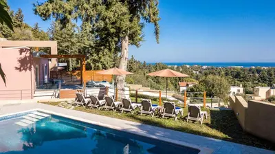 a swimming pool with lounge chairs and umbrellas at Louloudi Hills Villa 2 in Koskinou