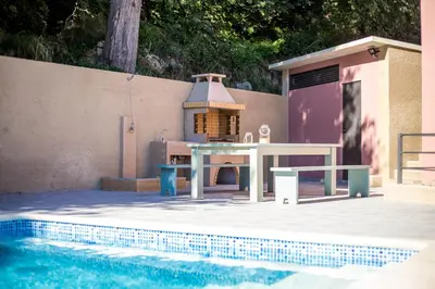 a patio with a table next to a swimming pool at Louloudi Hills Villa 2 in Koskinou