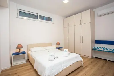a white bedroom with a bed and a window at Louloudi Hills Villa 2 in Koskinou