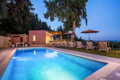 a swimming pool with chairs and a house at Louloudi Hills Villa 2 in Koskinou