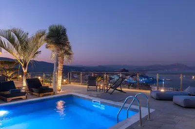 a swimming pool with a view of the ocean at night at Vitzi Vista Villa in Rhodes Town