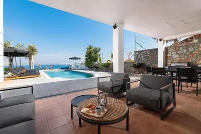 a patio with chairs and a table and a pool at Vitzi Vista Villa in Rhodes Town