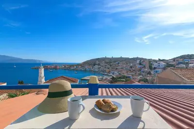 a table with a hat and a plate of food on a balcony at Yellow Oasis traditional home with sea view in Halki