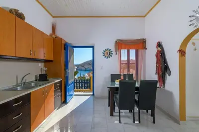a kitchen with a table and chairs and a view at Yellow Oasis traditional home with sea view in Halki