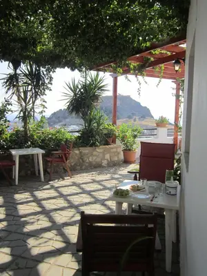 a patio with tables and chairs and a view of the ocean at Chrysa Studios in Líndos
