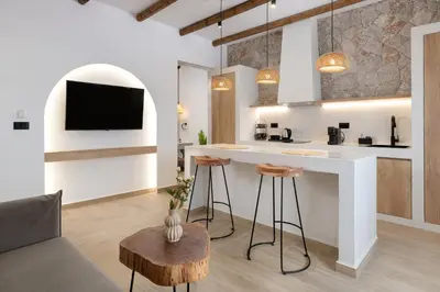 a kitchen and living room with a bar with stools at Onar Luxury Suites - Jacuzzi Terrace in Archangelos