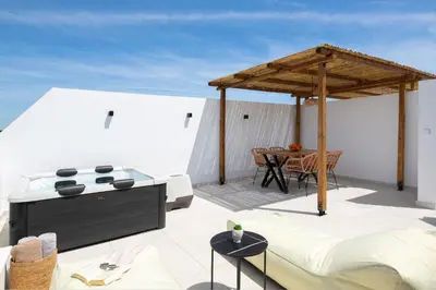 a patio with a bed and a table on a roof at Onar Luxury Suites - Jacuzzi Terrace in Archangelos