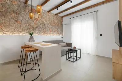 a kitchen and living room with a stone wall at Onar Luxury Suites - Jacuzzi Terrace in Archangelos