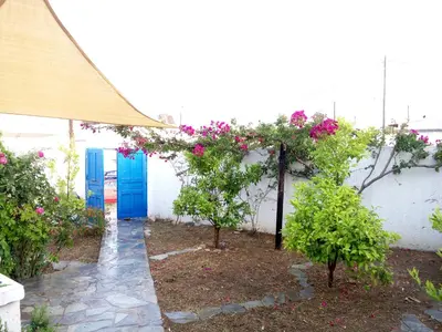 a white building with blue doors and pink flowers at Rhodes Summer House in Gennadi
