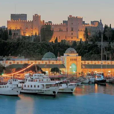 a group of boats in a harbor with a castle in the background at 3 Charites Old Town in Rhodes Town