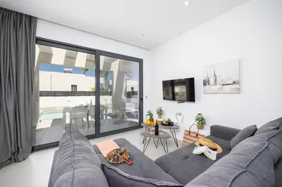 a living room with a gray couch and a table at Villa Salty Sun 1 in Kremasti