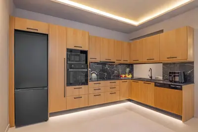 a kitchen with wooden cabinets and a black refrigerator at Olympus Luxury Villa Rhodes in Koskinou