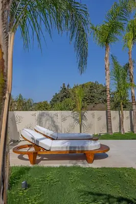 a bench with two surfboards on it next to palm trees at Olympus Luxury Villa Rhodes in Koskinou