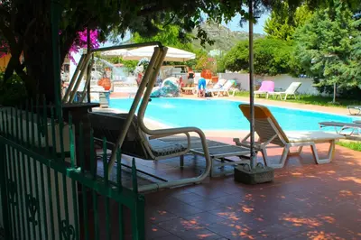 a pool with two chairs and a table and an umbrella at Melody Studios Faliraki in Faliraki
