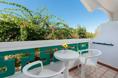 a table and chairs on a balcony with flowers at Melody Studios Faliraki in Faliraki
