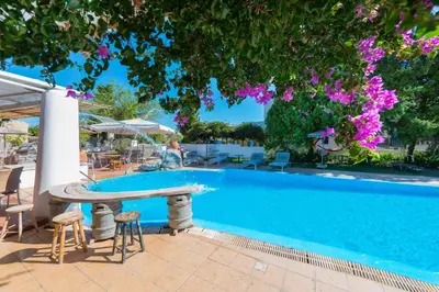 a pool with a table and chairs and a tree at Melody Studios Faliraki in Faliraki