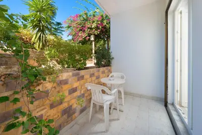 a patio with two white chairs and a table at Melody Studios Faliraki in Faliraki