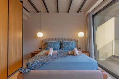 a bedroom with a blue bed with two pillows at Vadis Luxury Villa Rhodes in Koskinou