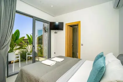 a bedroom with a bed and a large window at Villa Palm Vista by Villa Plus in Kremasti