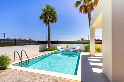 a swimming pool in a backyard with palm trees at Villa Palm Vista by Villa Plus in Kremasti