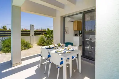 a white table and chairs on a patio with a view at Villa Palm Vista by Villa Plus in Kremasti