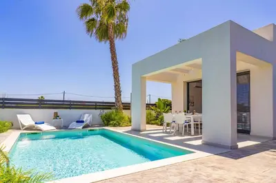 a villa with a swimming pool in front of a house at Villa Palm Vista by Villa Plus in Kremasti