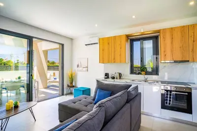 a living room with a couch and a kitchen at Villa Palm Vista by Villa Plus in Kremasti