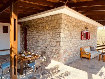 a patio with a table and chairs and a stone wall at Thomas house in Archangelos